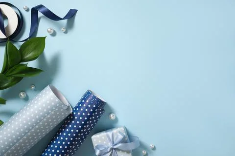 Blue wrapping paper rolls, scissors, and pearls on blue background. Copy spac Stock Photos