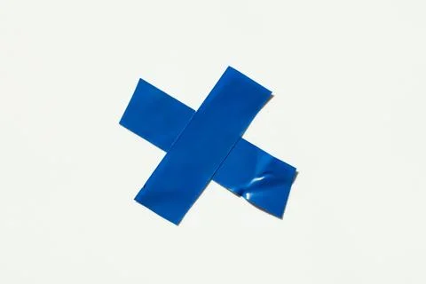 A blue X-shaped mark made of electrical tape on a white background. A symbol  Stock Photos