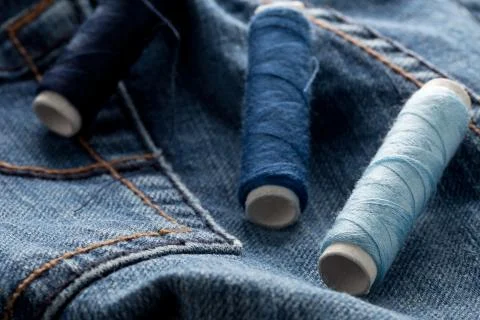 Blue yarn thread rolls on blue jeans denim close up - jeans fashion mending o Foto stock