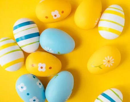 Blue, yellow and white Easter eggs on yellow background. Stock Photos