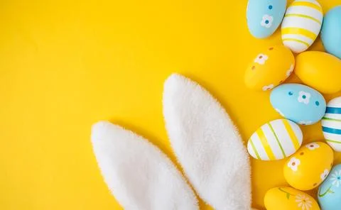 Blue, yellow and white Easter eggs on yellow background. Stock Photos
