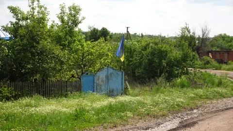 Blue-yellow flag waves proudly on a old fence in Kharkivska oblast. The scene Stock Footage 319835220