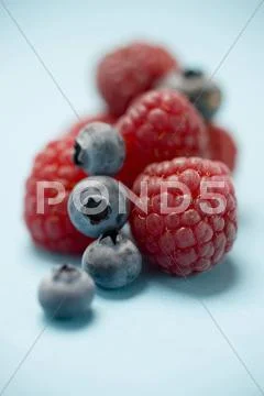 Blueberries and raspberries on blue background Stock Photos