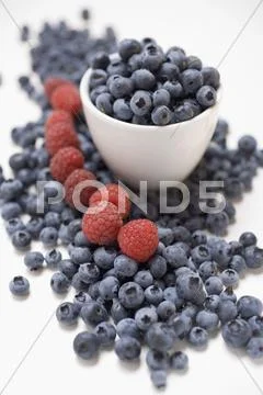 Blueberries and raspberries, some in bowl Stock Photos