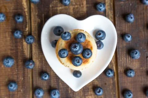 Blueberries and stack of mini pancakes on a heart-shaped plate Stockfoto's