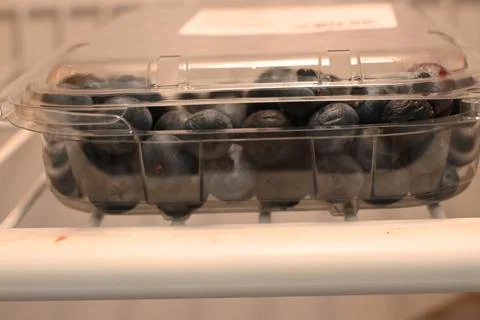 Blueberries in a clear container inside a refrigerator Фото