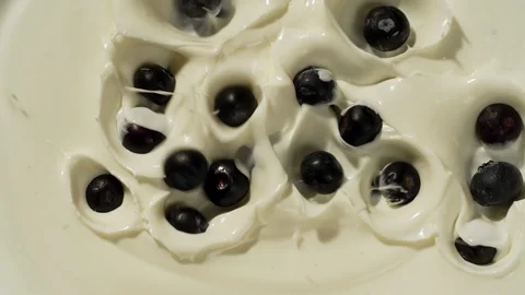 Blueberries falling in yogurt slow motion top view Stock Footage 124798416