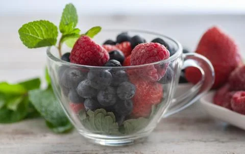 Blueberries strawberries and mint leaves in a glass dish. Stock Photos
