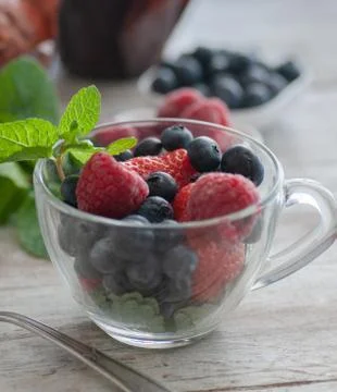 Blueberries on a table in a white saucer and in an old cup Stock Photos