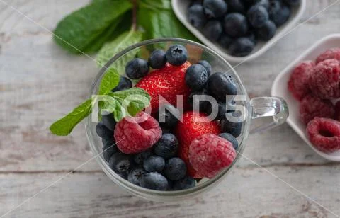 Blueberries on a table in a white saucer and in an old cup Stock Photos