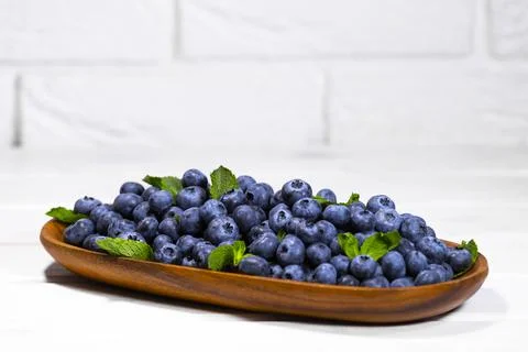 Blueberry and Raspberry With a Green Mint leaf in a Wooden Bowl on a white Stock Photos