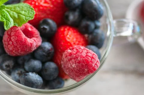 Blueberry raspberry strawberry and mint leaves in a glass dish. Stock Photos