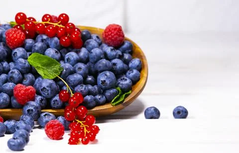 Blueberry, Red Currant and Raspberry With a Green Mint leaf in a Wooden Bowl Stock Photos