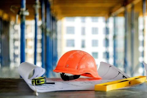 Blueprints project building, construction level and helmet, close up. Constru Stock Photos