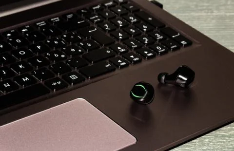 Bluetooth ear phone resting on the notebook Stock Photos