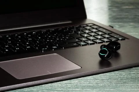 Bluetooth ear phone resting on the notebook Stock Photos