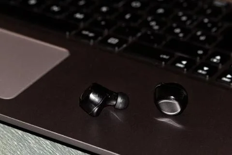 Bluetooth ear phone resting on the notebook Stock Photos