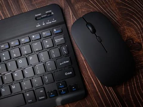 Bluetooth wireless keyboard and wireless mouse on a wooden background. Stock Photos
