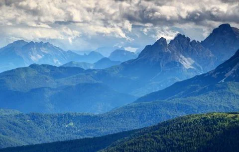 Bluish mist and dark clouds over forested ridges Dolomiti Italy Stock Photos