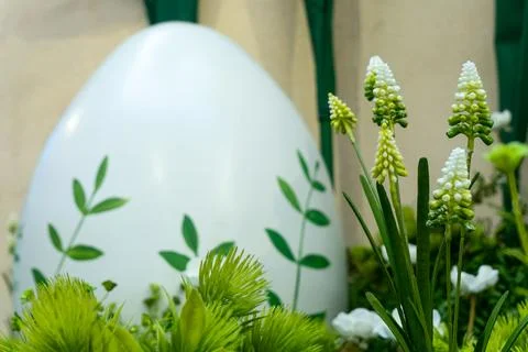Blur large white easter egg decorated with green leaves in garden. Spring f.. Stock Photos