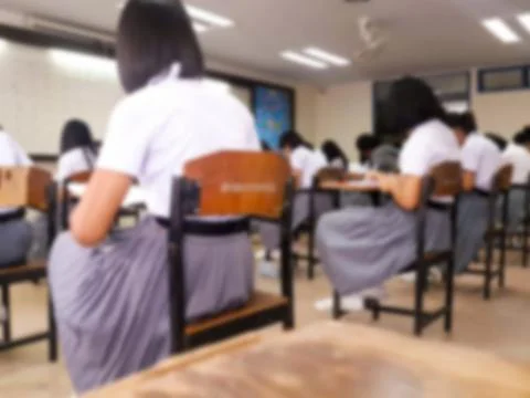 Blur  university students writing answer doing exam in classroom Stock Photos