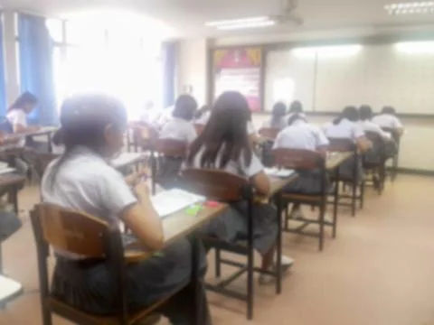 Blur  university students writing answer doing exam in classroom Stock Photos