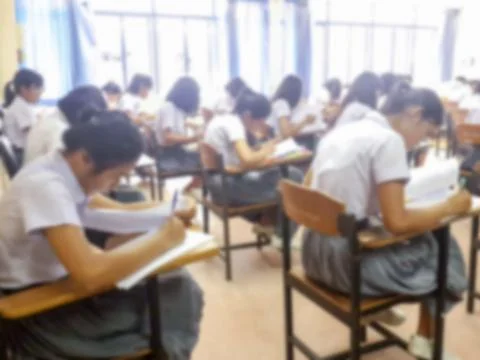 Blur  university students writing answer doing exam in classroom Stock Photos