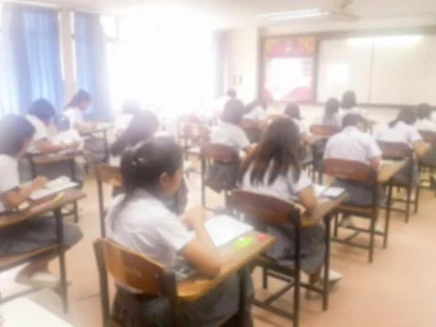 Blur  university students writing answer doing exam in classroom Stock Photos