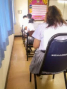 Blur  university students writing answer doing exam in classroom Stock Photos