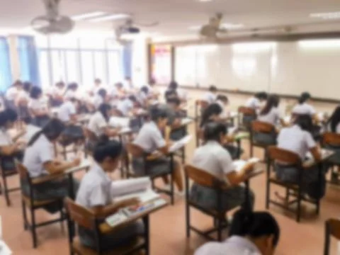 Blur  university students writing answer doing exam in classroom Stock Photos