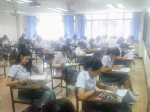 Blur  university students writing answer doing exam in classroom Stock Photos