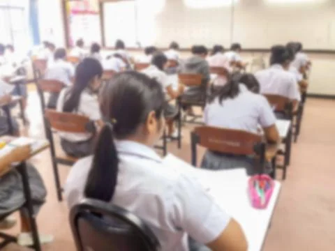 Blur  university students writing answer doing exam in classroom Stock Photos