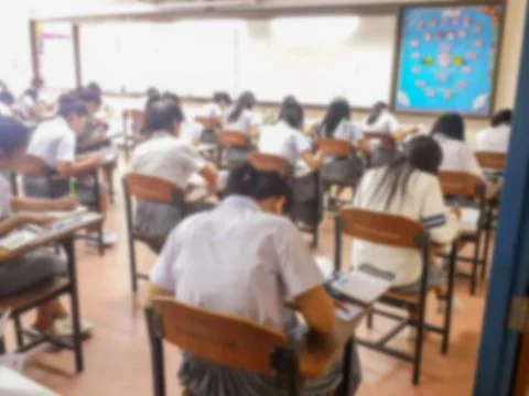 Blur  university students writing answer doing exam in classroom Stock Photos