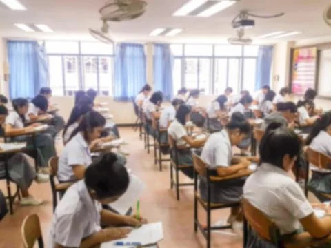 Blur  university students writing answer doing exam in classroom Stock Photos