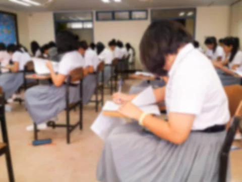 Blur  university students writing answer doing exam in classroom Stock Photos