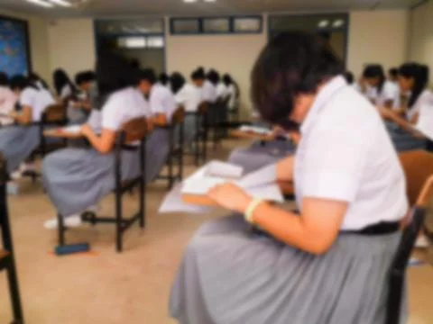 Blur  university students writing answer doing exam in classroom Stock Photos
