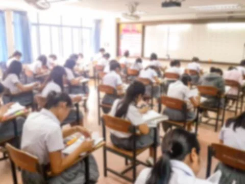 Blur  university students writing answer doing exam in classroom Stock Photos