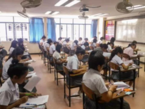 Blur  university students writing answer doing exam in classroom Stock Photos