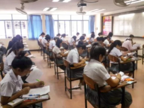 Blur  university students writing answer doing exam in classroom Stock Photos