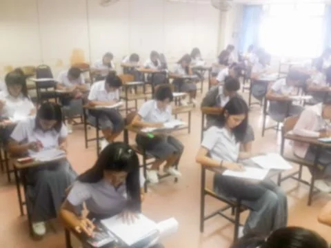Blur  university students writing answer doing exam in classroom Stock Photos