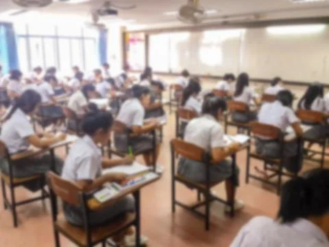 Blur  university students writing answer doing exam in classroom Stock Photos