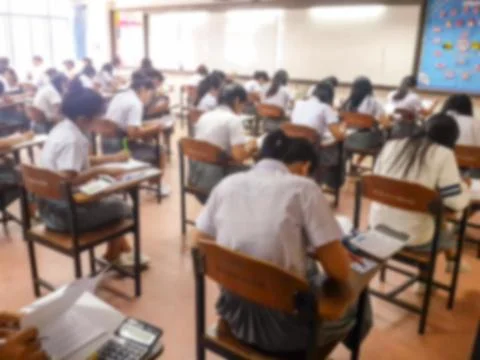 Blur  university students writing answer doing exam in classroom Stock Photos