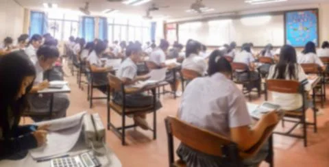 Blur  university students writing answer doing exam in classroom Stock Photos