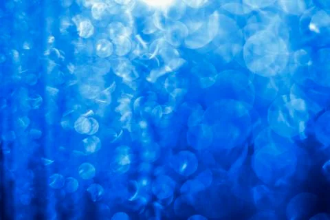 Blurred abstract blue glitter texture, defocused christmas lights on black ba Stock Photos