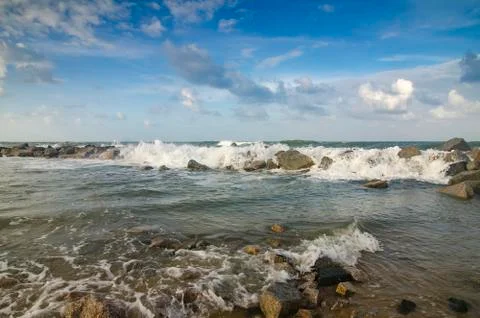 Blurred and selective focus image of wave hitting breakwater on the beach ove Stock Photos