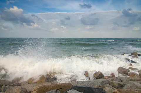 Blurred and selective focus image of wave hitting breakwater on the beach ove Stock Photos