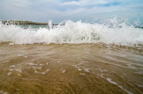 Blurred and selective focus image of wave hitting the beach over cloudy and b Foto stock