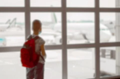 Blurred back view of a boy with red backpack in the waiting room at the airpo Stock Photos