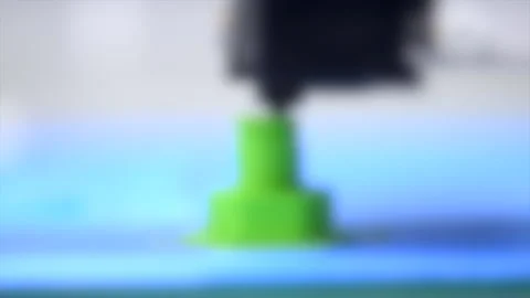 Blurred background. 3D printer makes or printing bolt model, screw green 動画素材 134907219