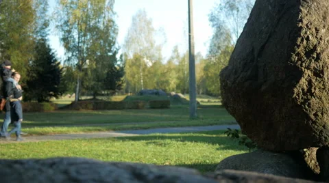 Blurred Background: the father and two sons walking in the park of large stones Stock Footage 68578515